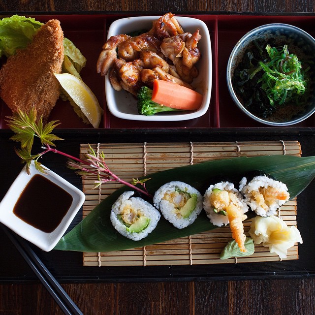 Japanese bento meal with sushi rolls, grilled chicken, fried cutlet, seaweed salad, and dipping sauce by Lish catering.