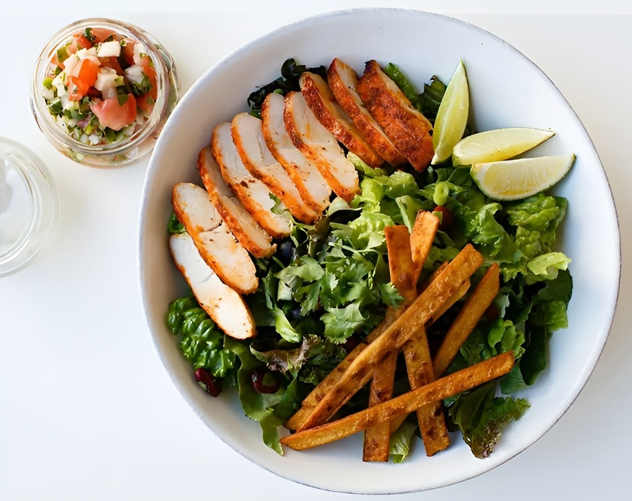 Lish's salad bowl with grilled chicken, lettuce, tortilla strips, lime wedges and a side of fresh salsa.