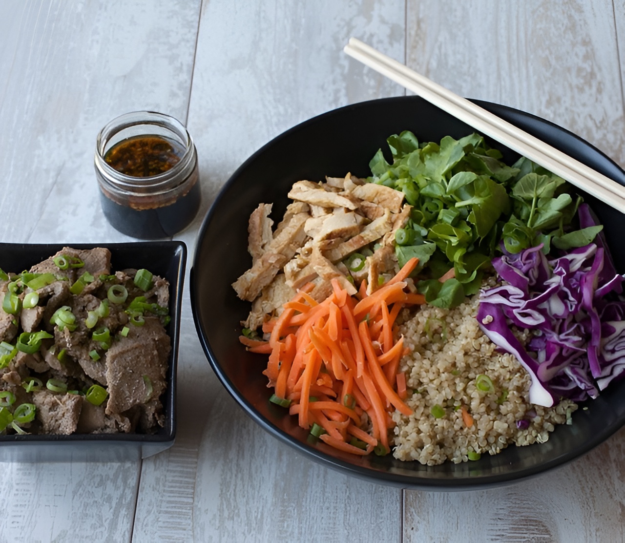 A bowl from Lish catering with quinoa, grilled tofu, carrots, cabbage, greens, served next to a meat side dish.