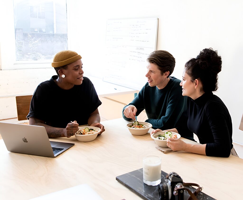 Three co-workers smiling and enjoying office meals catered by Lish.