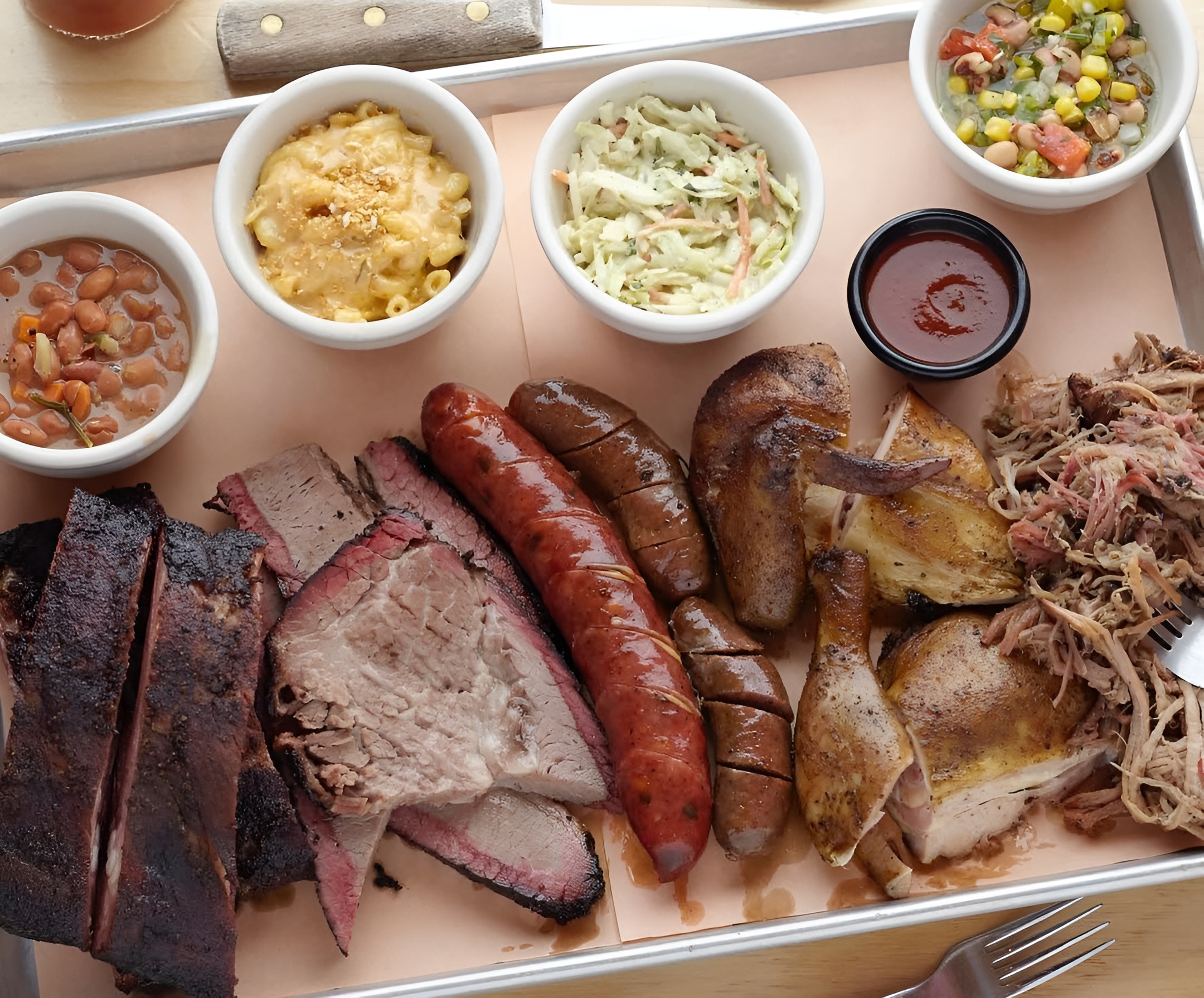 BBQ platter with ribs, sausage, chicken, pulled pork with sides, and salad.