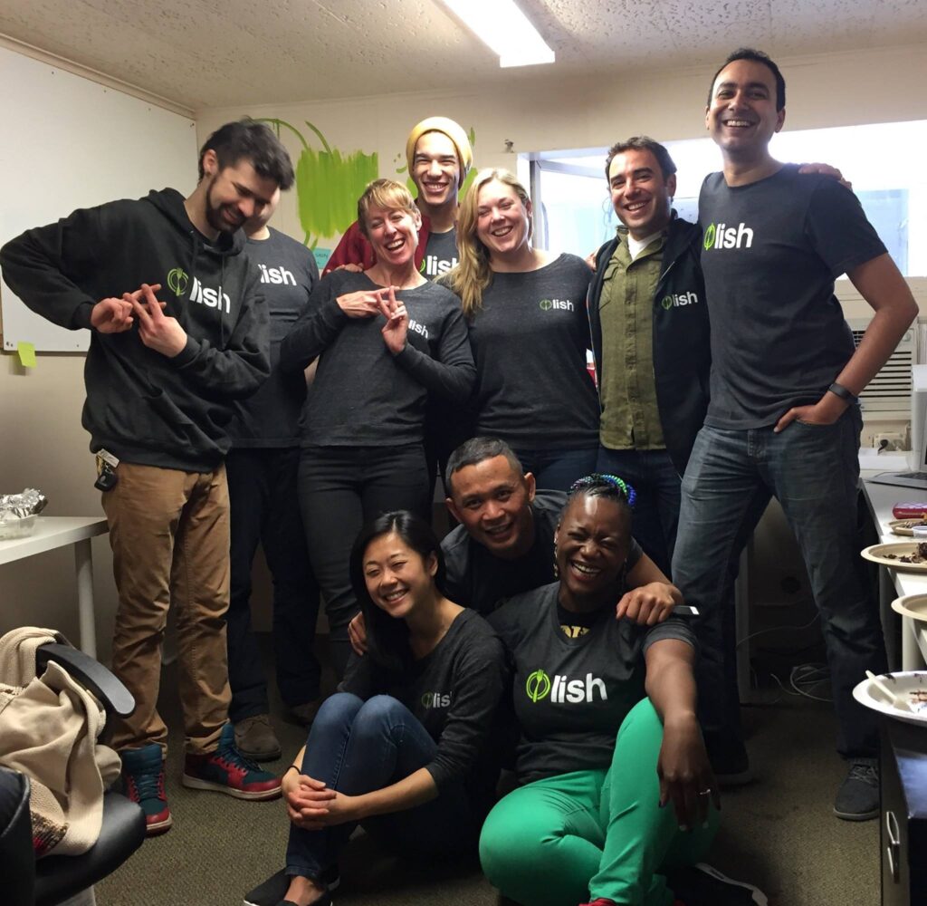 A diverse group of people smiling and posing for a team photo wearing a hoodie with a Lish logo on it.
