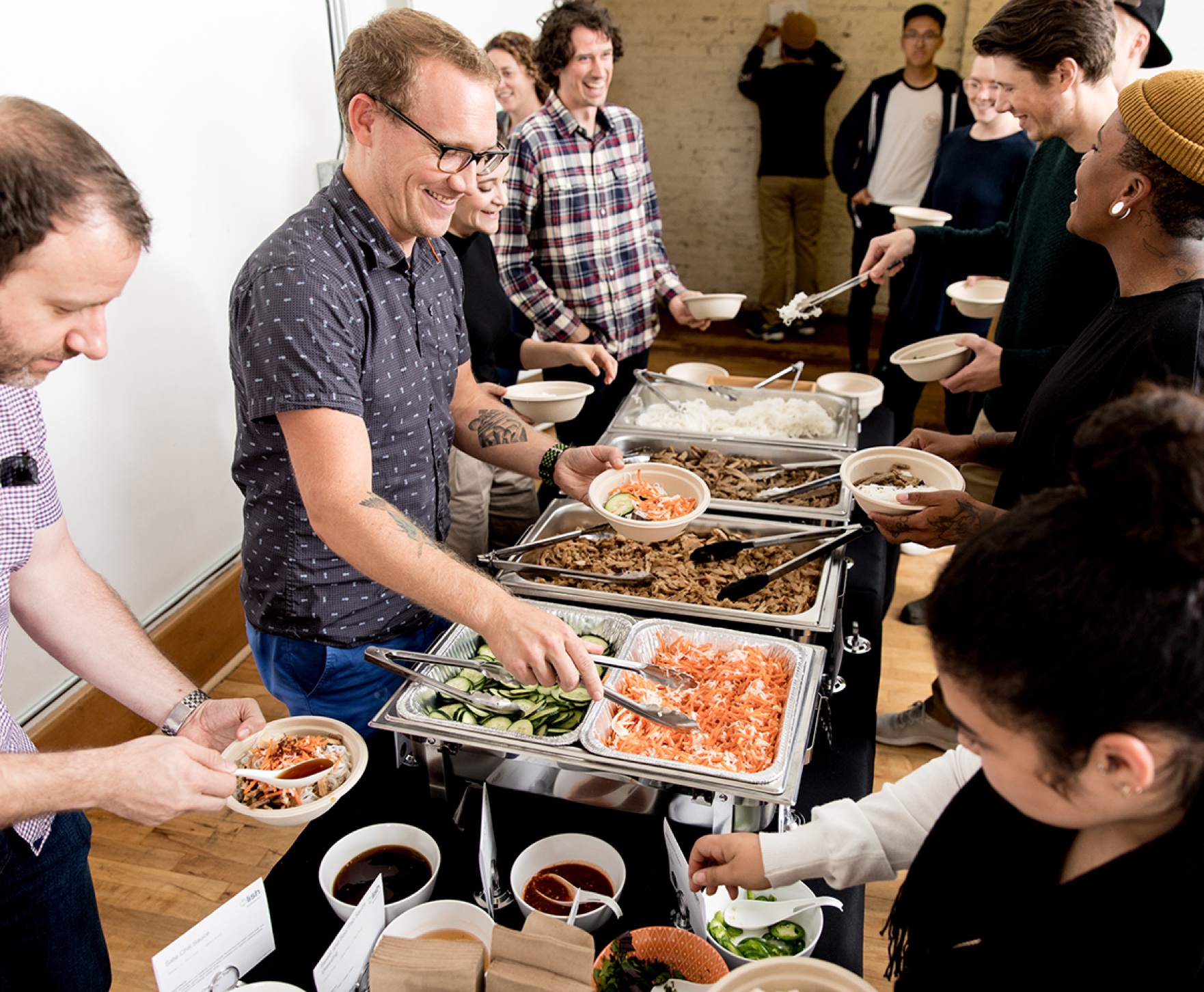 Office employees serving themselves lunch from a sustainable catering spread provided by Lish in Seattle.