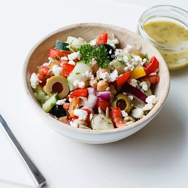 A bowl of Mediterranean salad featuring olives, feta, peppers, and fresh greens from Lish.