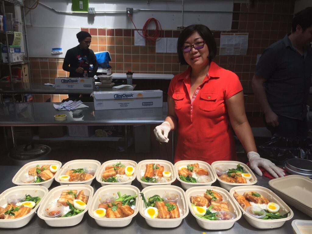  Chef preparing packaged meal boxes with salmon, eggs, and greens for Lish catering service.