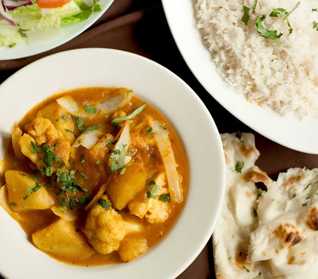 Indian vegetable curry, naan, rice, and salad, catered by Lish in plates displayed on the table.